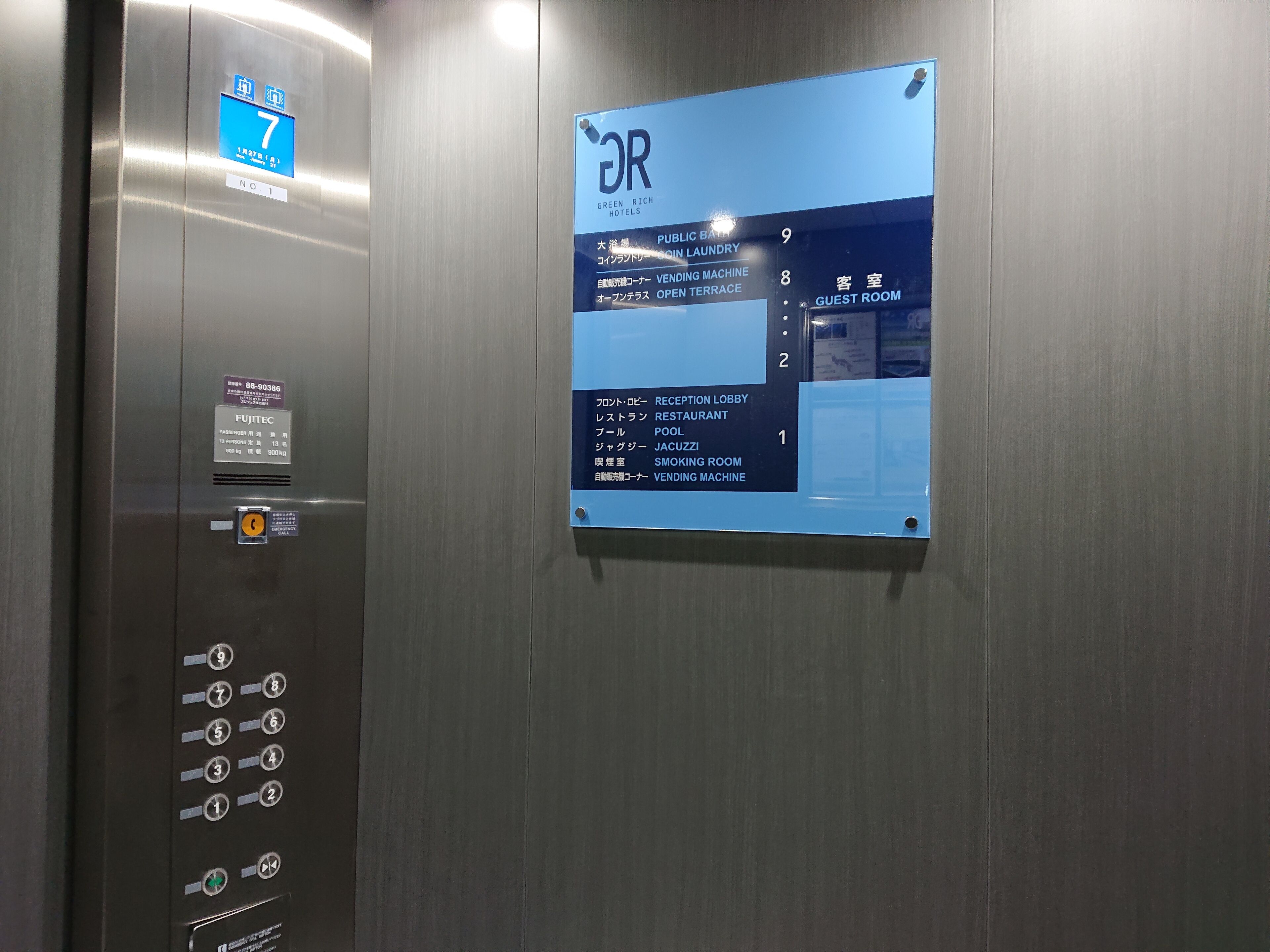 An elevator interior with a digital display indicating floor 7, a Fujitec sign, and a directory listing amenities including a public bath, guest room, reception lobby, restaurant, pool, jacuzzi, smoking room, and vending machine.