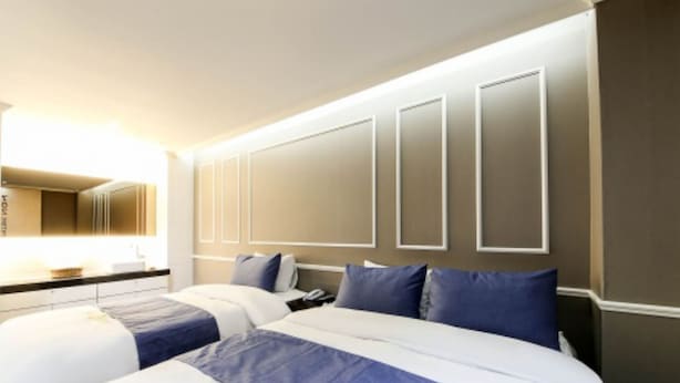 A hotel room with a large bed, a bedside table, and a mirror. - Shilla E Stay Motel (Yeosu)