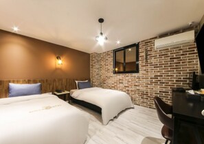 A hotel room with two beds, a desk, a chair, a brick wall, and an air conditioning unit. - Shilla E Stay Motel (Yeosu)