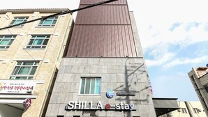 A hotel named SHILLA e-stay with a modern design, featuring a prominent sign and a visible window. - Shilla E Stay Motel (Yeosu)