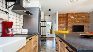 Una cocina moderna con una isla central, una pared de ladrillo y un televisor montado en la parte superior.