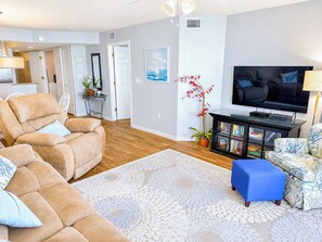 A living room with a sofa, a coffee table, a television, and a bookshelf.