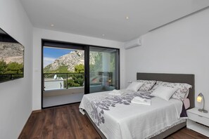 Un dormitorio moderno con una cama grande, una mesita de noche y vistas a un paisaje montañoso a través de un ventanal corredera.