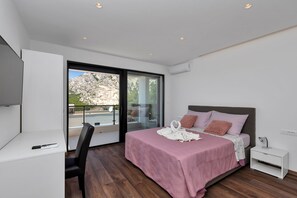 A modern bedroom with a bed, a desk, and a view of the outdoors. - Modern holiday home with infinity pool, three bedrooms, terrace, sea view (Bast)
