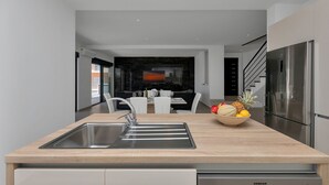 A modern kitchen with a built-in sink, a wooden countertop, and a stainless steel refrigerator. - Modern holiday home with infinity pool, three bedrooms, terrace, sea view (Bast)