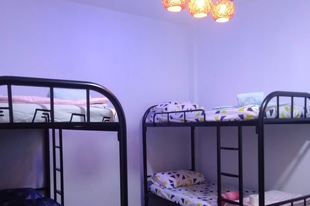 A dormitory room with bunk beds, a ceiling light fixture, and a patterned floor.