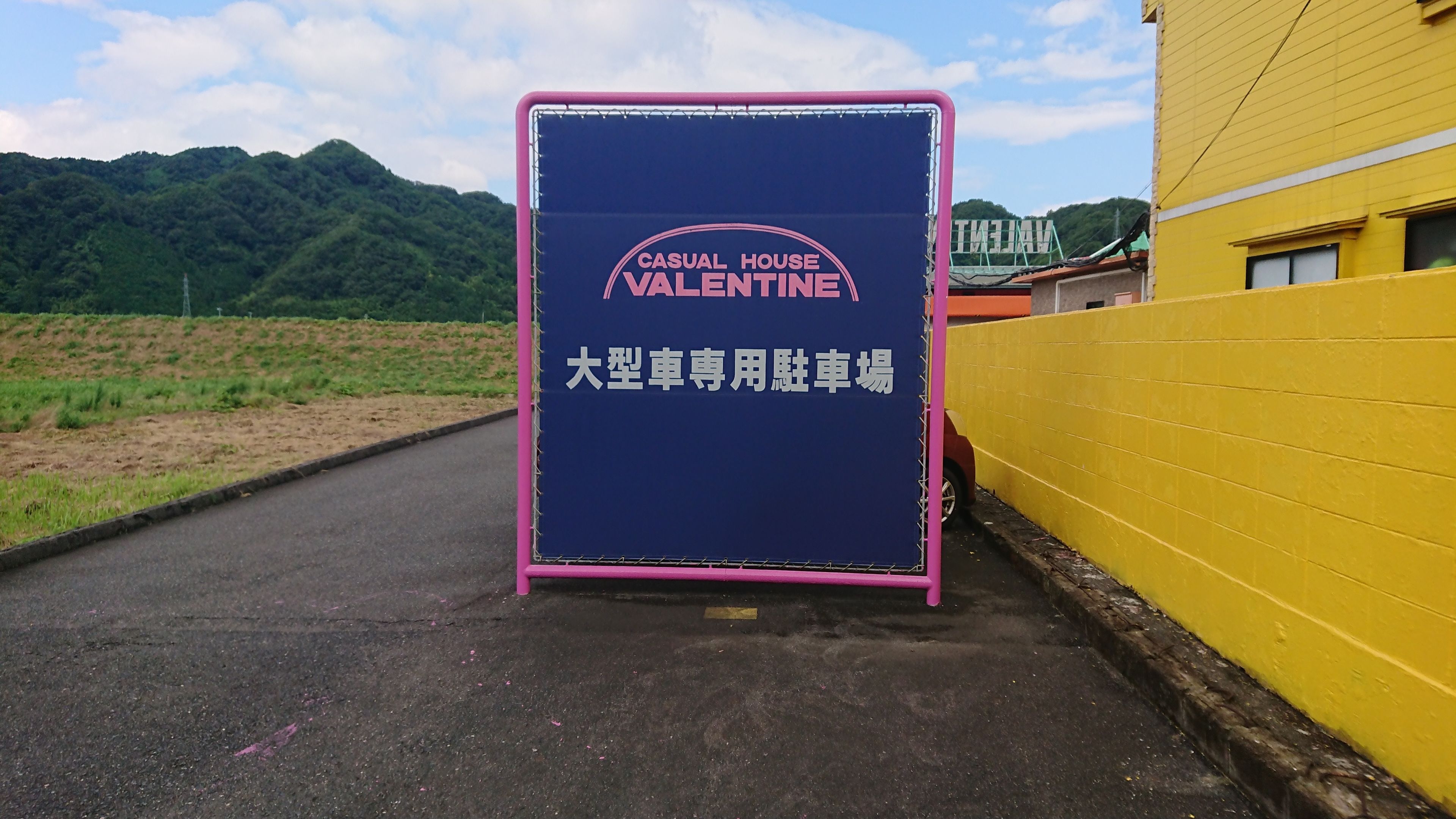 A sign for a hotel named "Casual House Valentine" with a large blue signboard and pink border.