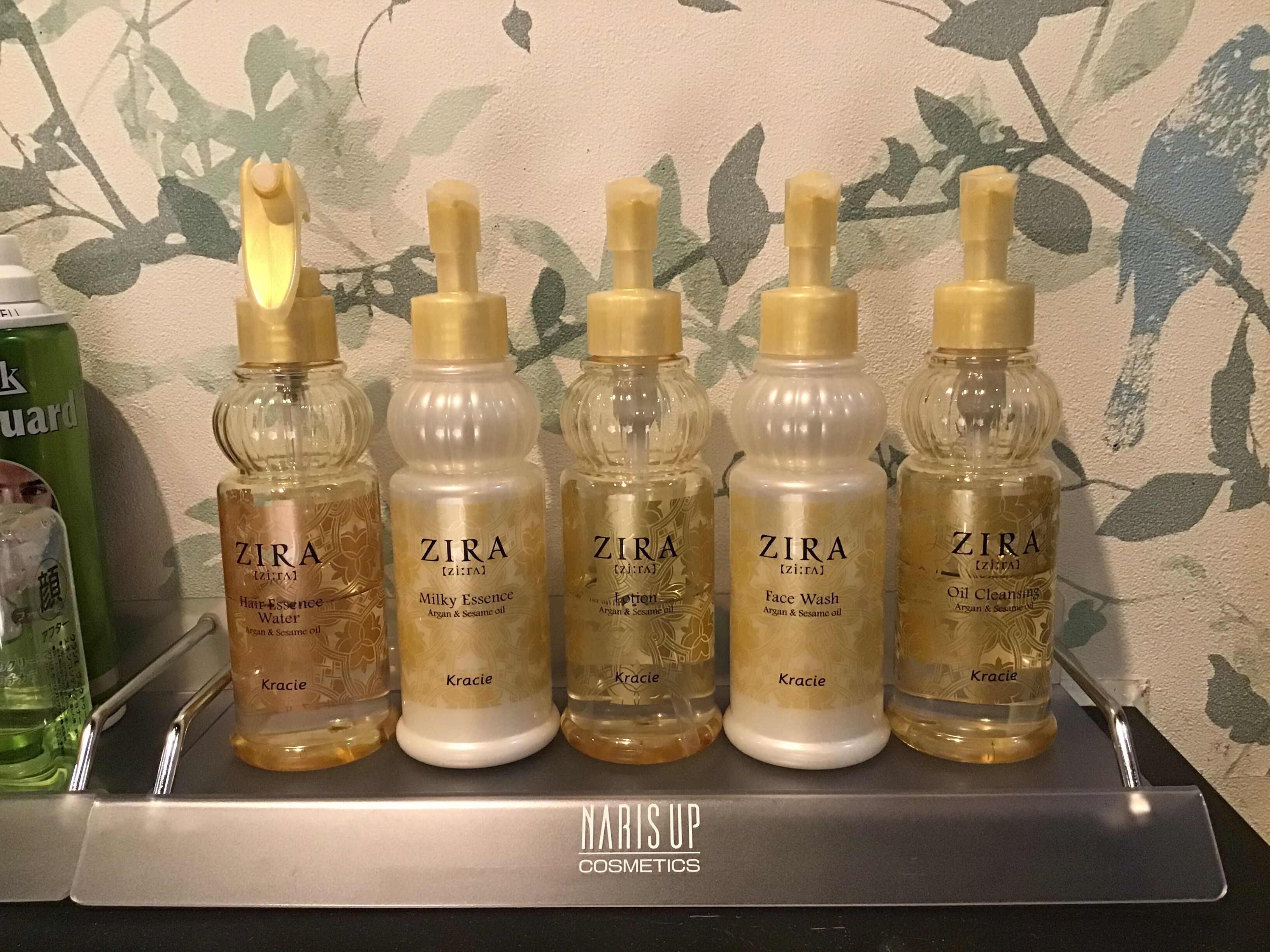 A display of ZIRA skincare products on a metal shelf with a floral wallpaper background.