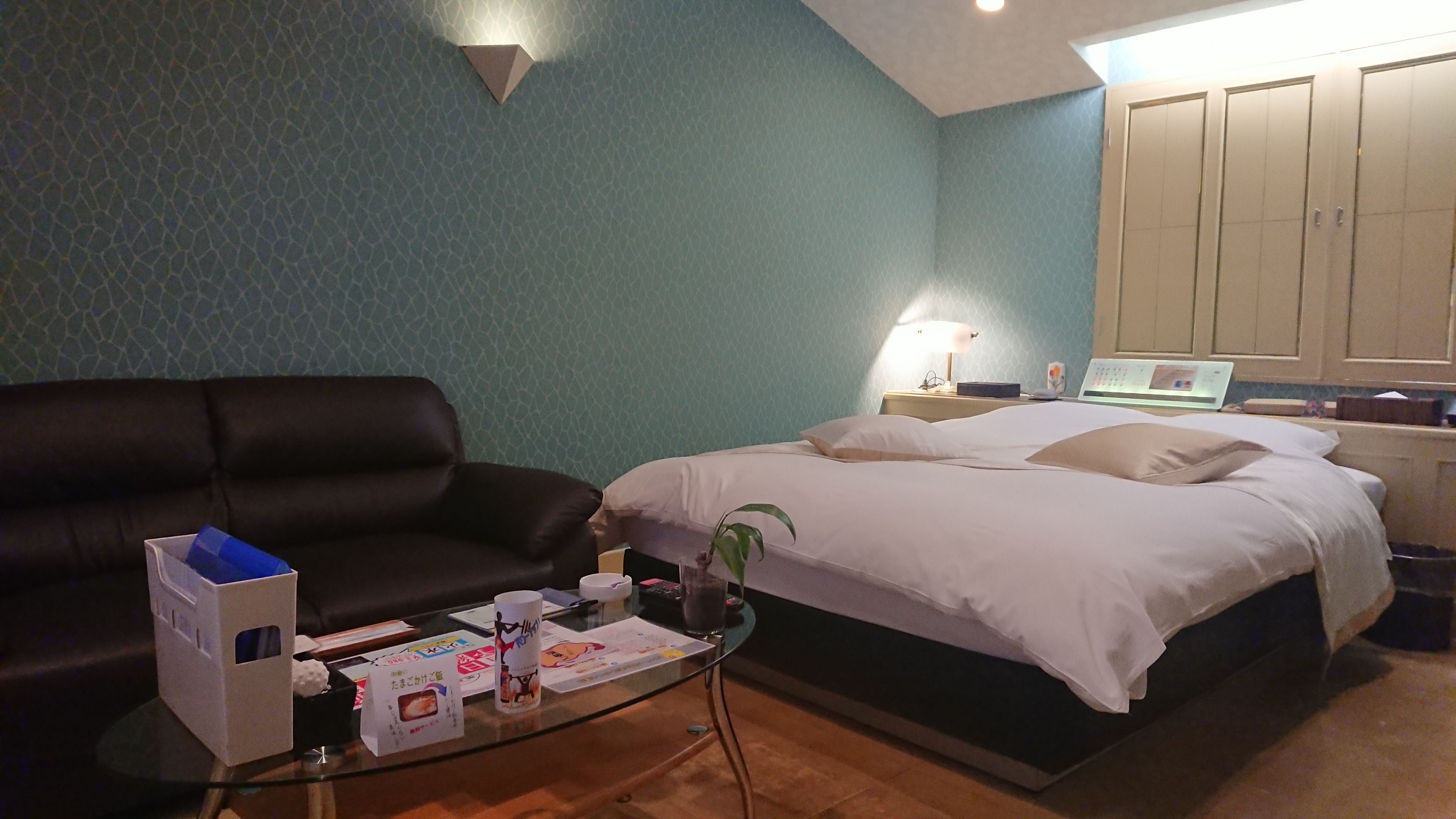 A hotel room with a bed, a desk, a laptop, a lamp, and a couch.