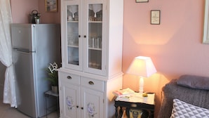 Un espace de vie compact comprenant un meuble blanc, une petite table avec une lampe et un canapé gris.