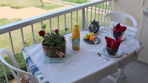 Un balcon avec une table dressée pour un repas, donnant sur une plage.