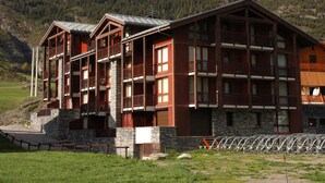 A multi-story wooden building with balconies, set against a mountainous backdrop.