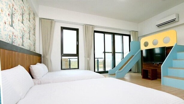 Une chambre d’hôtel avec deux lits, de grandes fenêtres, une télévision et un escalier.