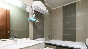 Une salle de bain équipée d’un lavabo, de toilettes et d’une baignoire, ainsi que d’un porte-serviettes placé au-dessus des toilettes.