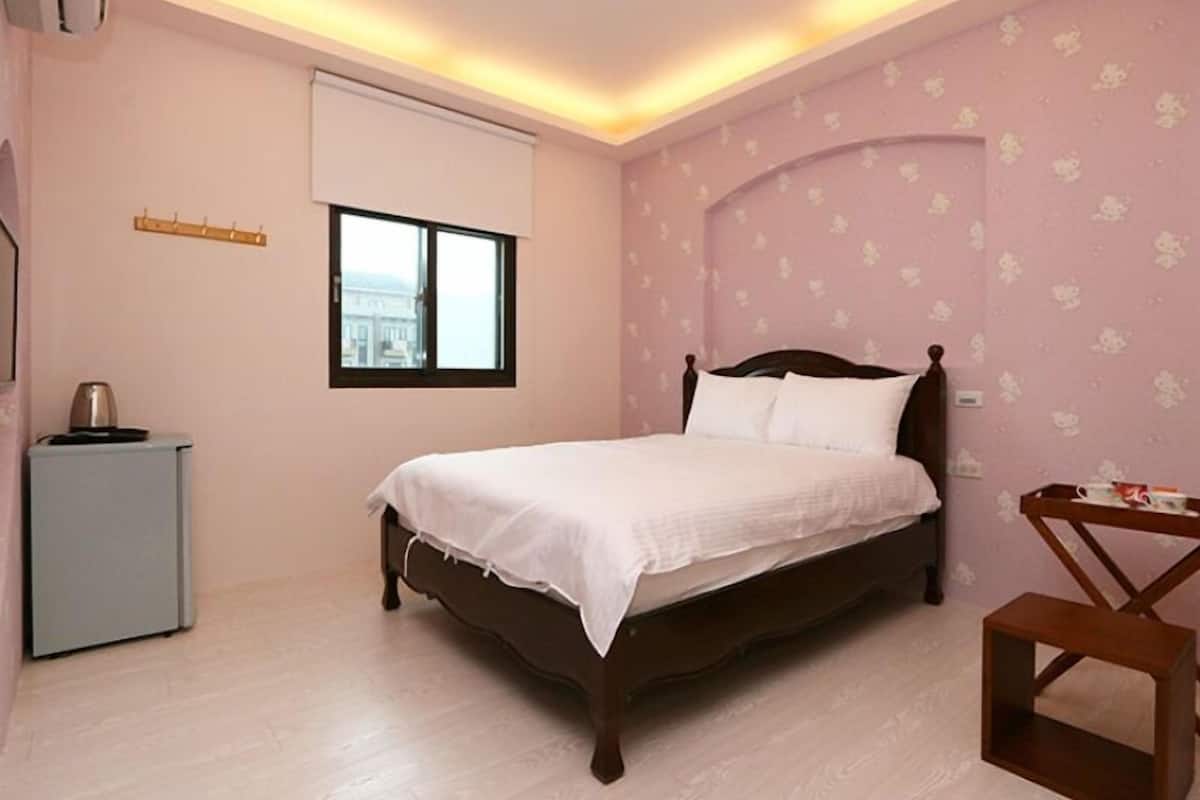 Een slaapkamer met een bed, een tafeltje, een raam en een radiator.