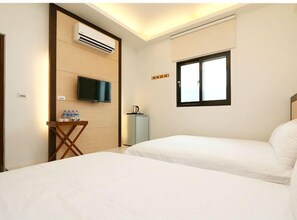 Une chambre d’hôtel avec deux lits, une télévision, la climatisation, un minibar et une fenêtre avec des stores.