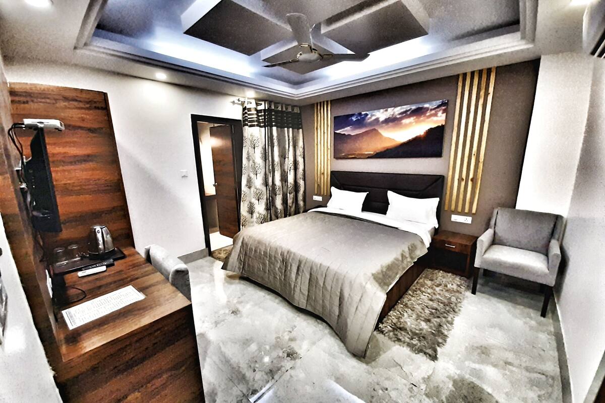 A modern bedroom with a large bed, a desk, and a chair.
