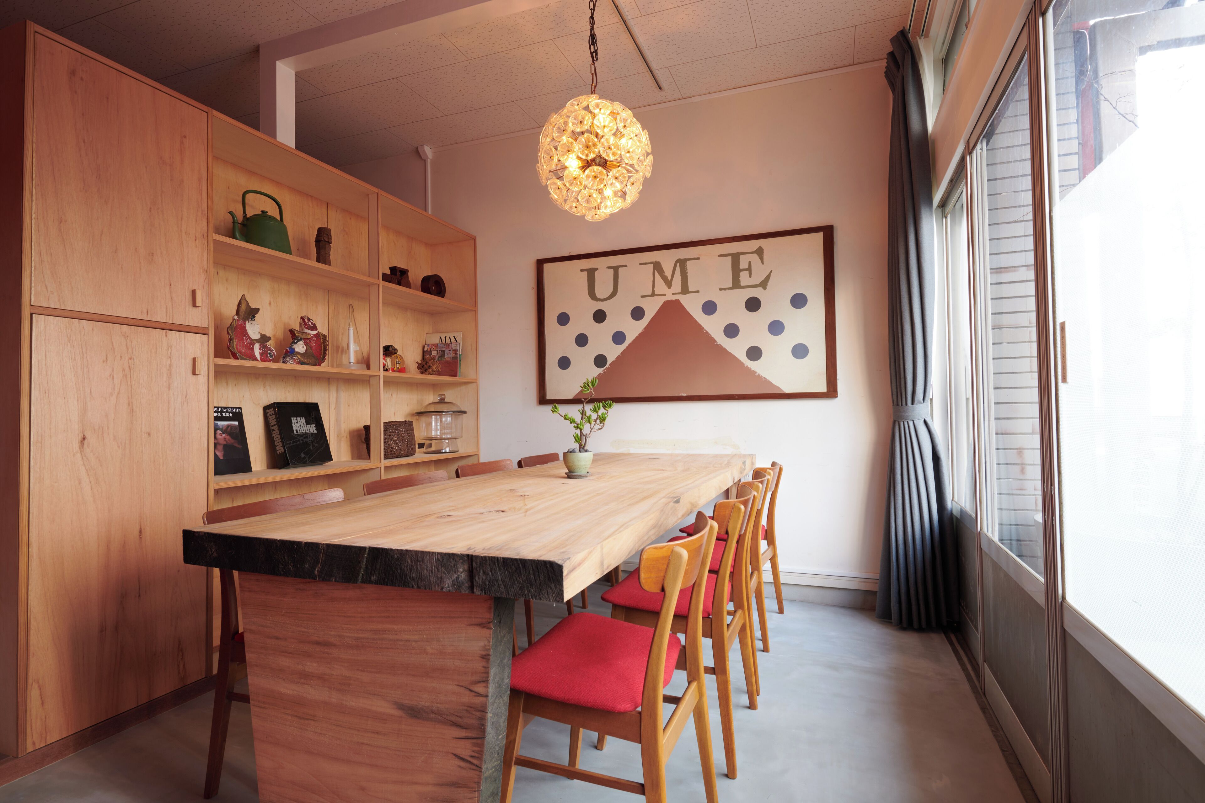 A dining area with a wooden table, red cushioned chairs, and a decorative light fixture.