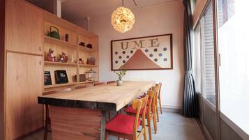 A dining area with a wooden table, red cushioned chairs, and a decorative light fixture.