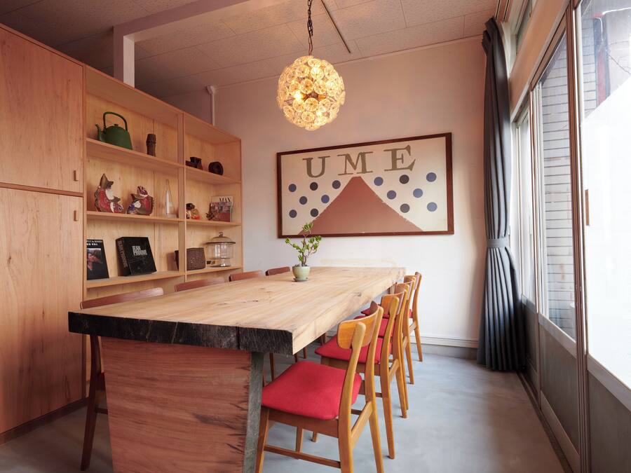 A dining area with a wooden table, red cushioned chairs, and a decorative light fixture.