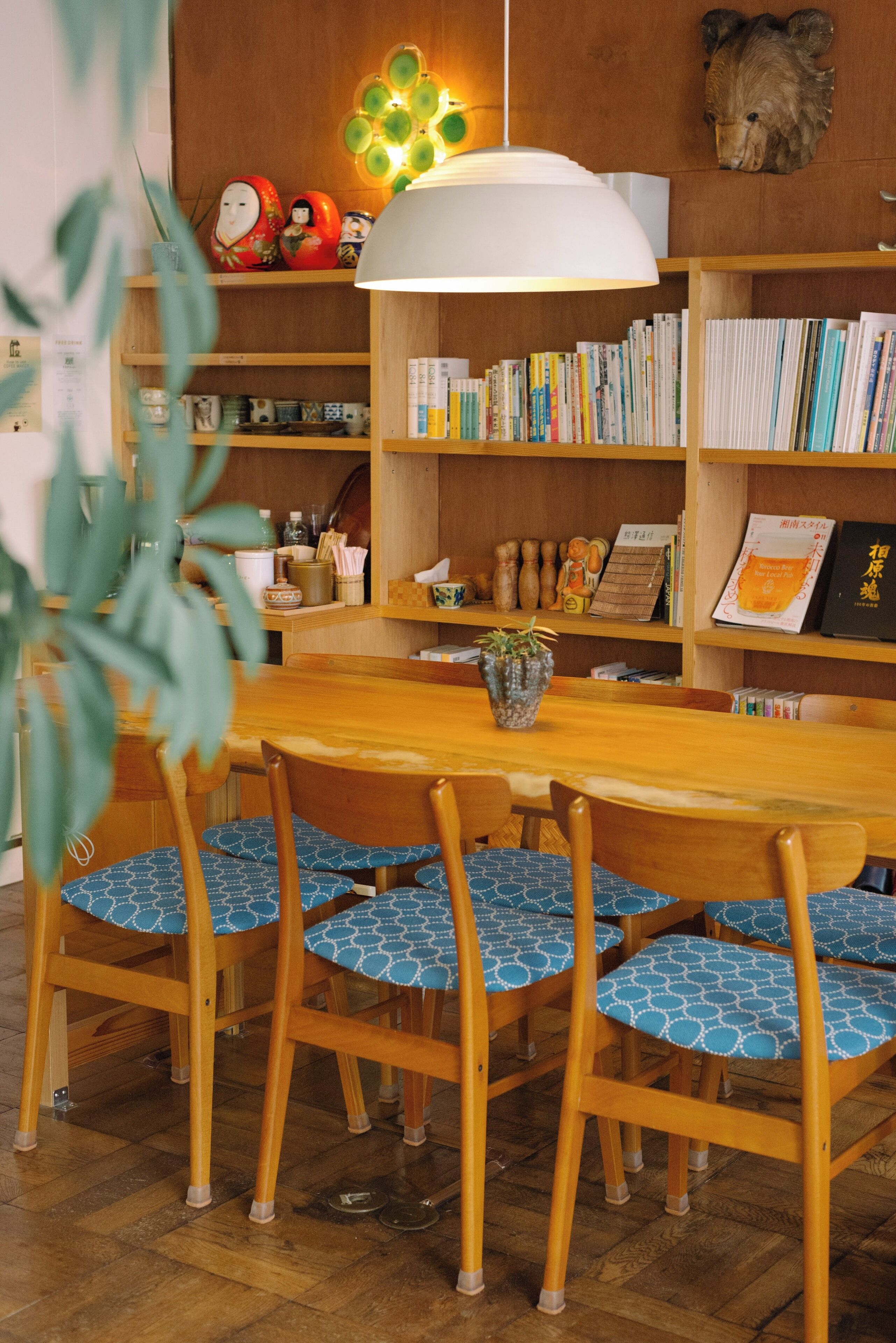 A dining area with a wooden table and chairs, surrounded by bookshelves filled with books and decorative items.