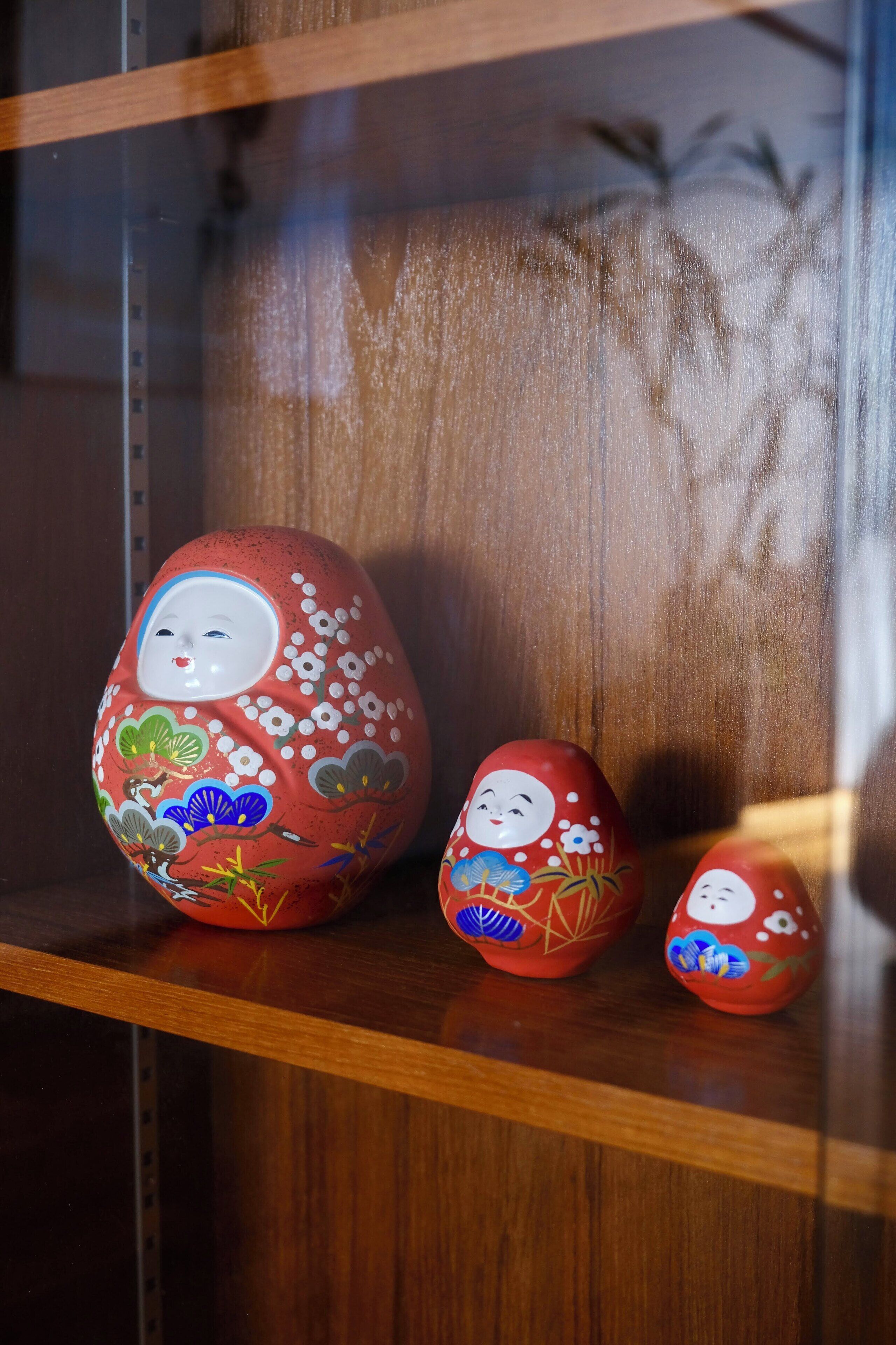 Three painted eggs on a wooden shelf.