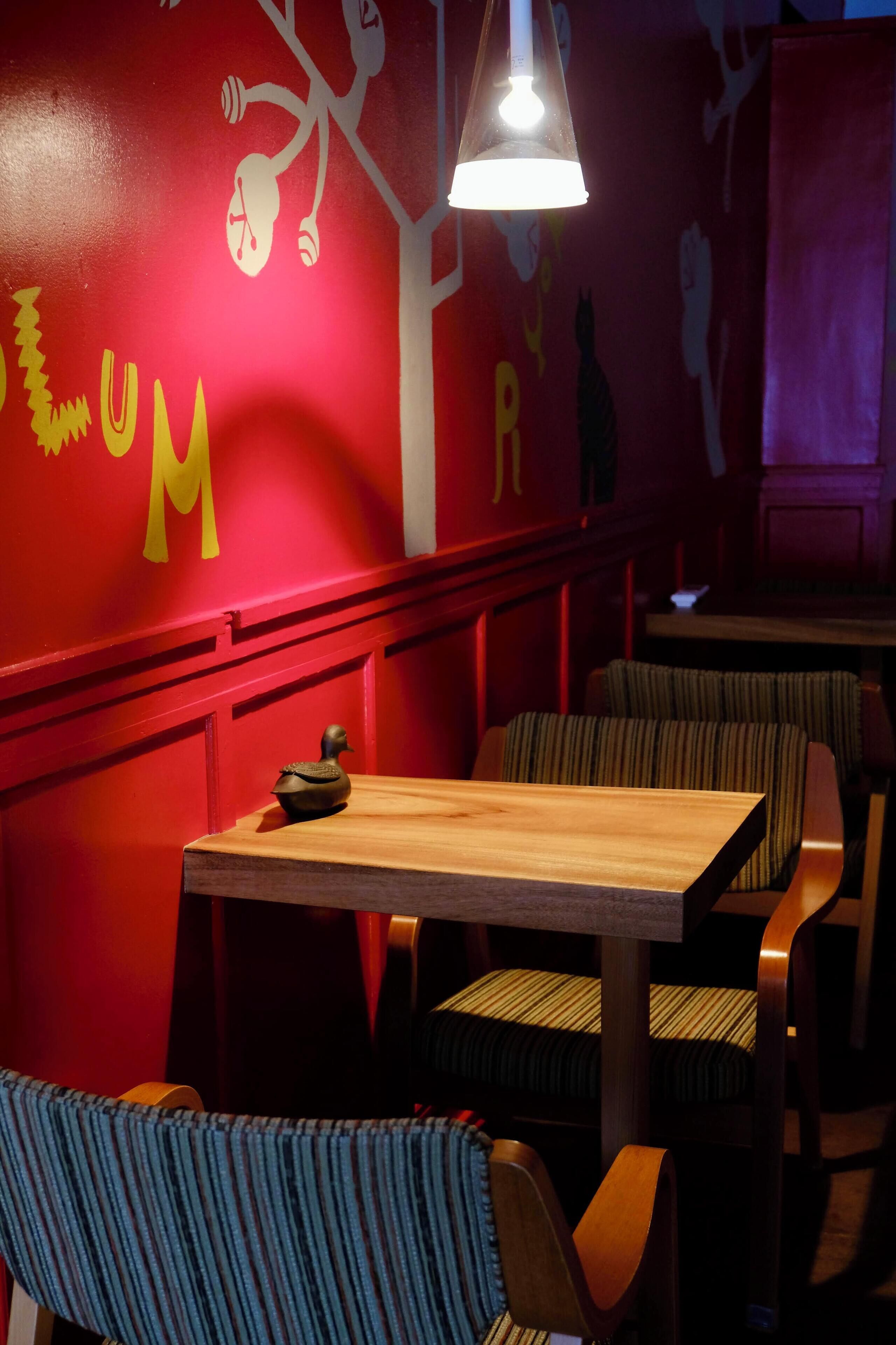 L’intérieur d’un restaurant avec des murs rouges, des tables en bois et des chaises rembourrées à rayures.
