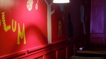 Interior de restaurante con paredes rojas, mesas de madera y sillas con cojines a rayas.