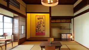 A traditional Japanese room with tatami flooring, a low table, and a sliding door. - RYOKAN PLUM (Odawara)