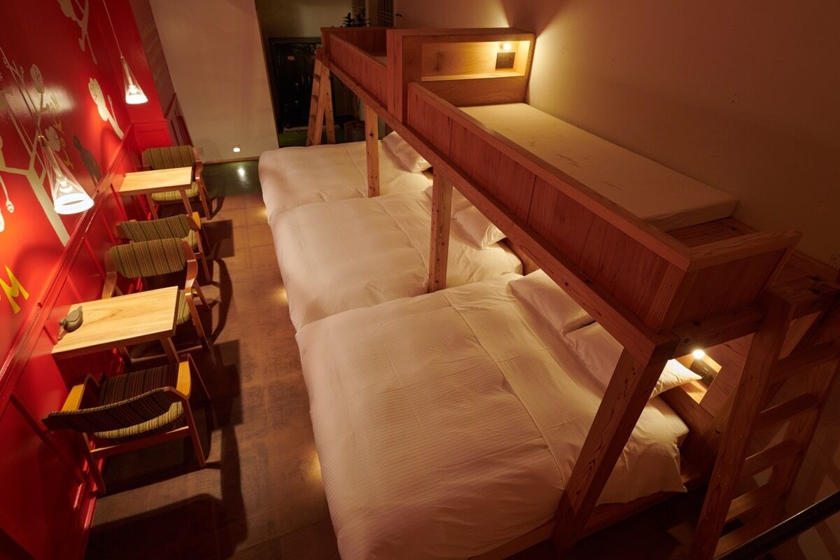 Habitación tipo dormitorio con literas, un escritorio de madera y sillas.
