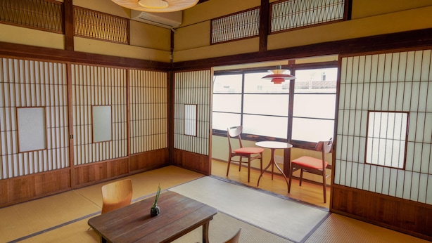 A traditional Japanese room with tatami flooring, shoji screens, and a low wooden table with a small plant. - RYOKAN PLUM (Odawara)
