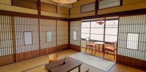 Ein traditioneller japanischer Raum mit Tatami-Böden, Shoji-Schirmen und einem niedrigen Holztisch mit einer kleinen Pflanze.