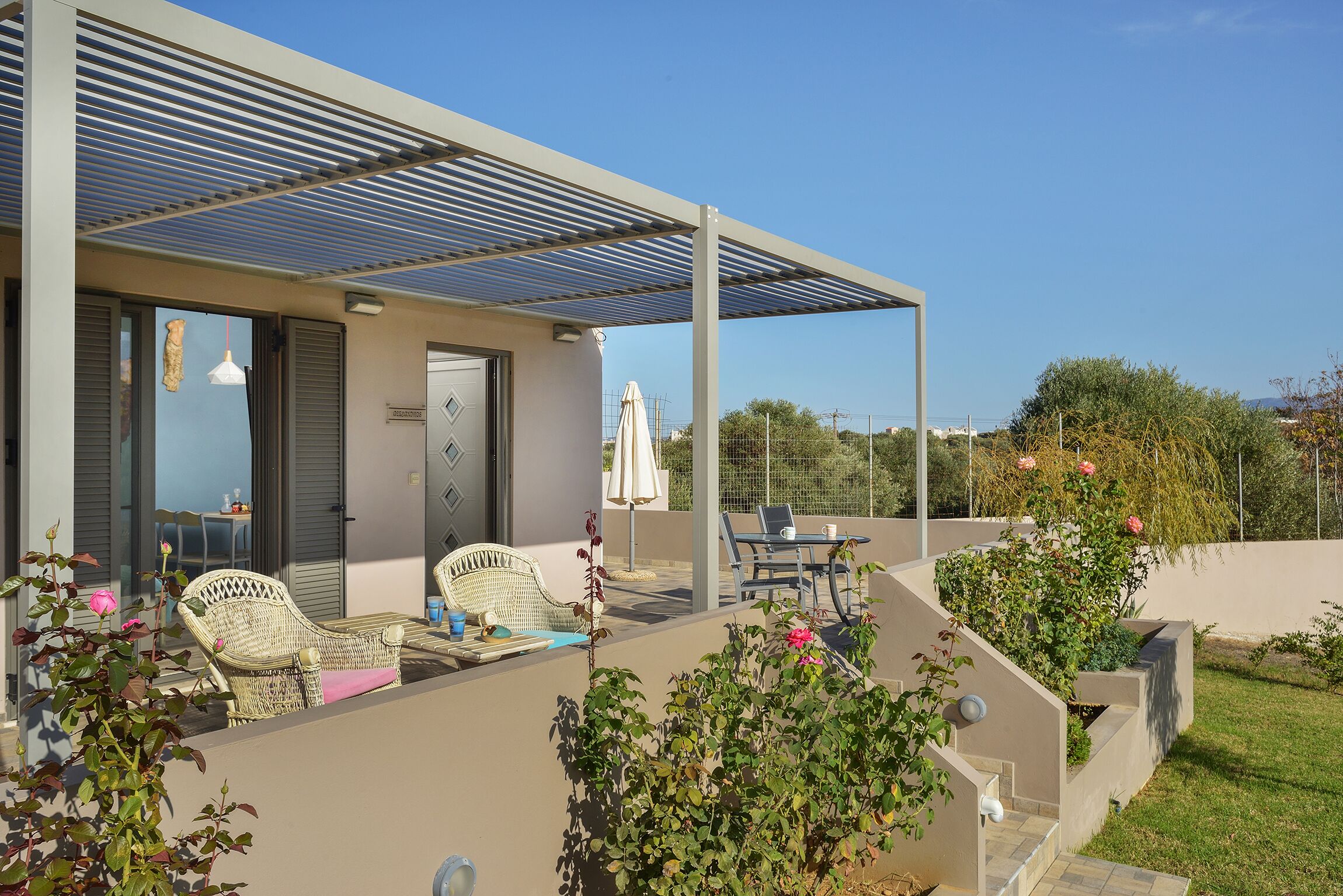 Un espace extérieur abrité, aménagé avec des meubles en osier, une table et une chaise.