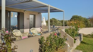 Un espace extérieur abrité, aménagé avec des meubles en osier, une table et une chaise.