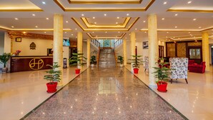 A hotel lobby with a reception desk, a staircase, and potted plants. - Hotel Leh Plaza (Leh)