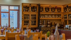 A restaurant with wooden furniture and a variety of dishes displayed on shelves. - Hotel Leh Plaza (Leh)