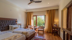 A hotel room with two beds, a desk, a chair, and a view of the outdoors. - Hotel Leh Plaza (Leh)