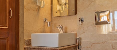 A modern bathroom with a marble sink, a toilet, a hand dryer, and a mirror.