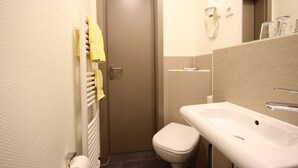 A small bathroom with a toilet, a sink, a towel rack, and a mirror. - Hotel Hanken (Wangerooge)