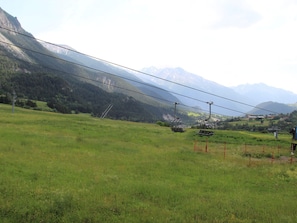 A grassy field with a mountain backdrop and a cable car system.