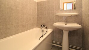 Une salle de bain avec une baignoire, un lavabo et un miroir.