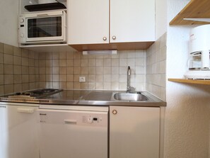 A compact kitchen with a microwave, stove, sink, and dishwasher.