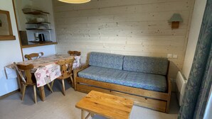 Un salon chaleureux avec un canapé, une table en bois et une table à manger avec des chaises.