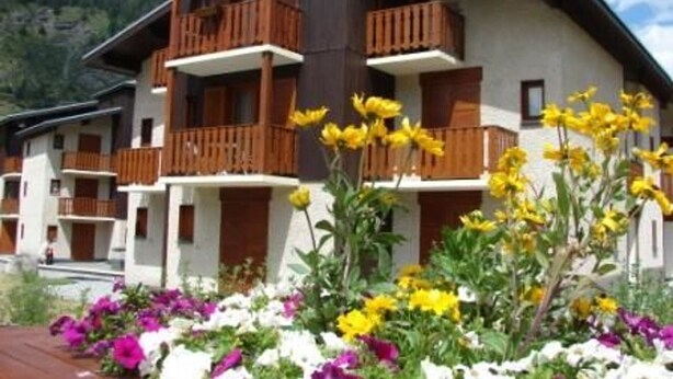 A multi-story chalet with wooden balconies and a mountain backdrop. - Cozy apartment for 4 with WIFI and parking in Lanslevillard (Lanslevillard)