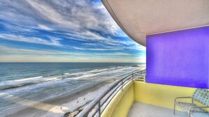 A balcony with a view of the beach and ocean, a purple wall, and a yellow floor. - 2/2 Deluxe Ocean walk (Daytona Beach)