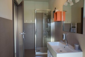 A modern bathroom with a glass shower enclosure, a white sink, and a mirror with a towel rack. - Foresteria La Merlina (Dernice)