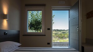 Ein Schlafzimmer mit Bett, Fenster und Blick auf eine Landschaft.