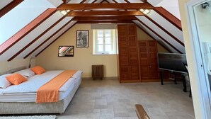 Une chambre avec un plafond en pente, un lit, un radiateur, une armoire et un piano.