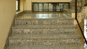 A staircase with granite steps leading to a landing with a stone wall and recessed lighting. - Hotel Tapas (Kathmandu)