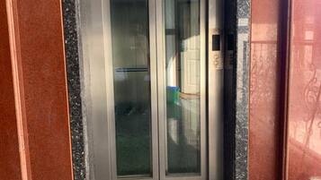 An elevator with glass doors and a granite floor.